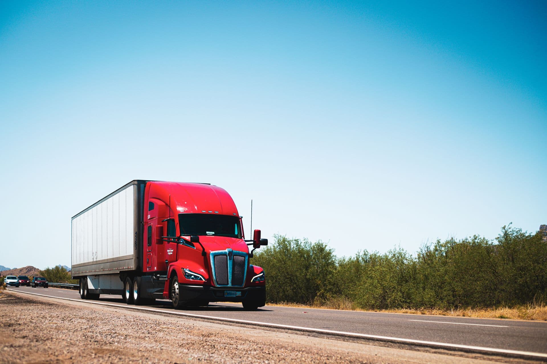 Red semi-trailer truck on an open highway under a clear sky