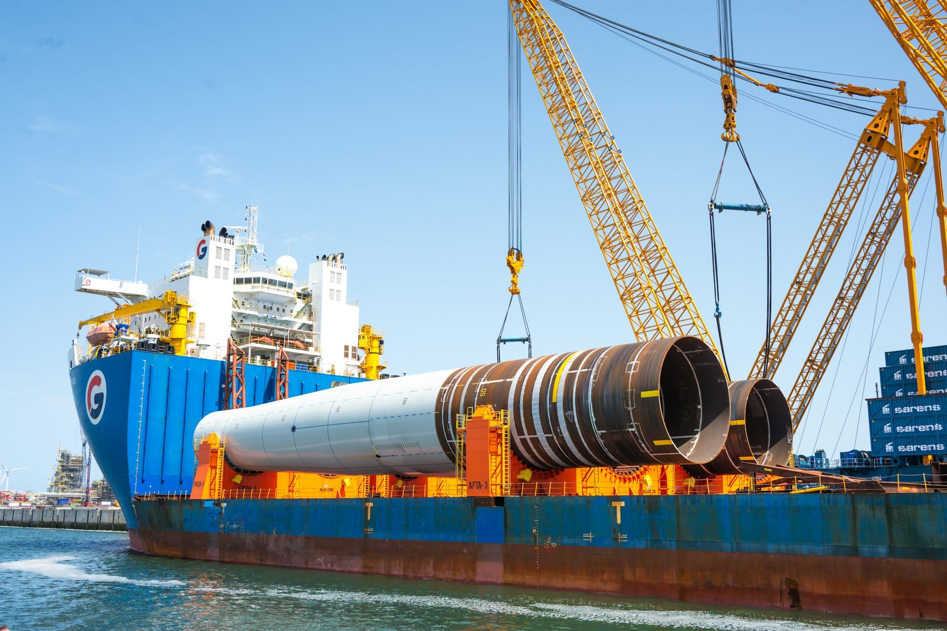 Heavy-lift cranes loading large cylindrical modules onto a vessel
